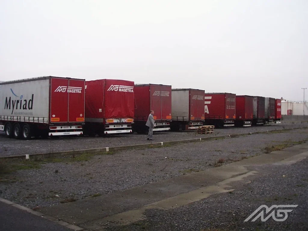 A row of curtain-sided semitrailers parked at a yard